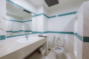 A bathroom with a sink, mirror, toilet, and a hand dryer. - Morakot Hotel Chumphon (Chumphon)