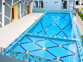 Una piscina con un diseño geométrico de mosaicos, rodeada por un edificio de estilo moderno.