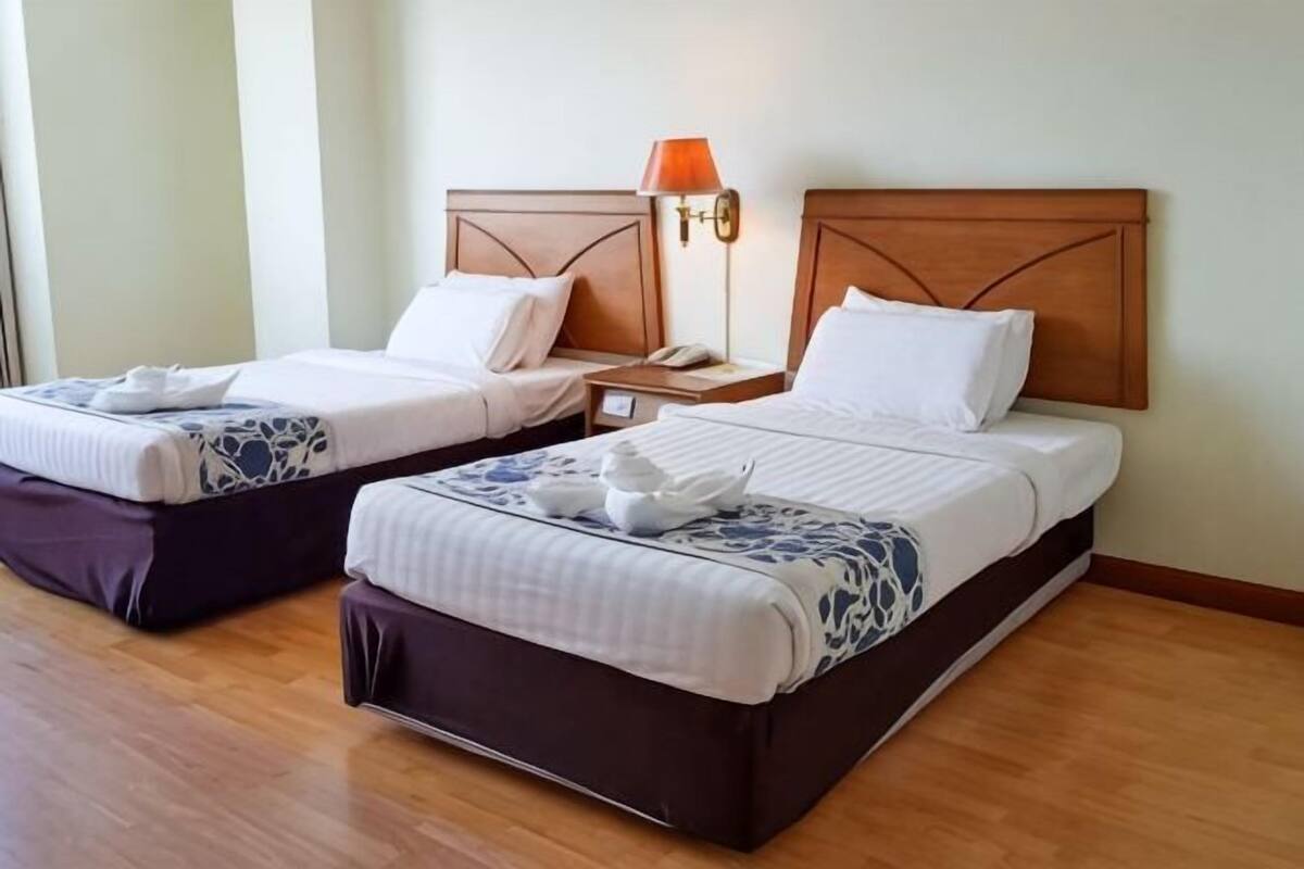 Two single beds with wooden headboards, bedside tables, and lamps.