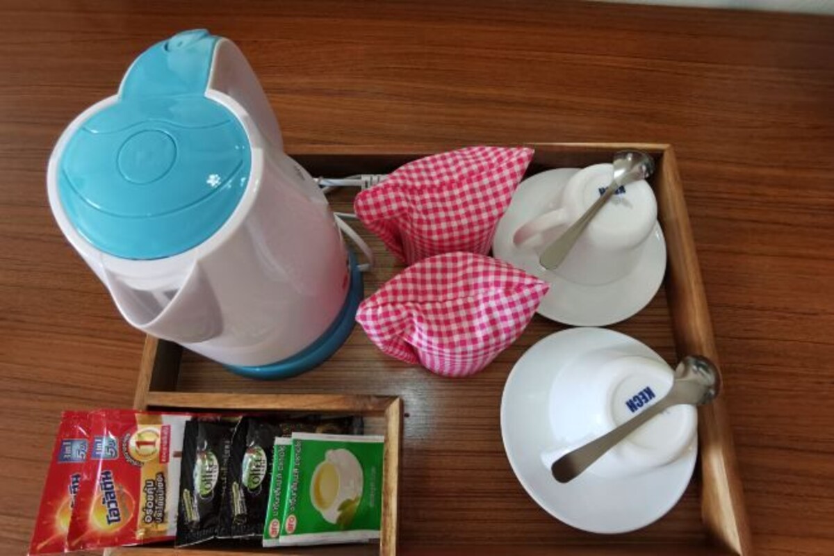 A tray with a coffee maker, cups, a spoon, and some food packets.