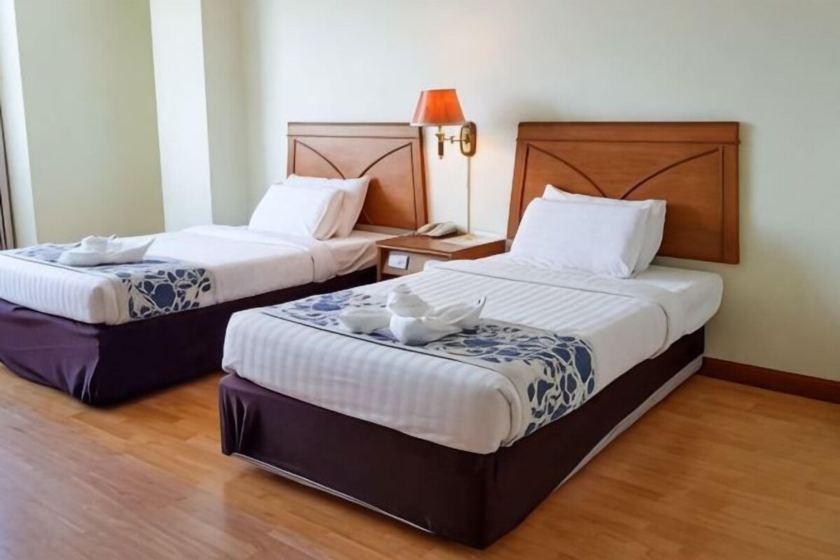 Two single beds with wooden headboards, bedside tables, and lamps.