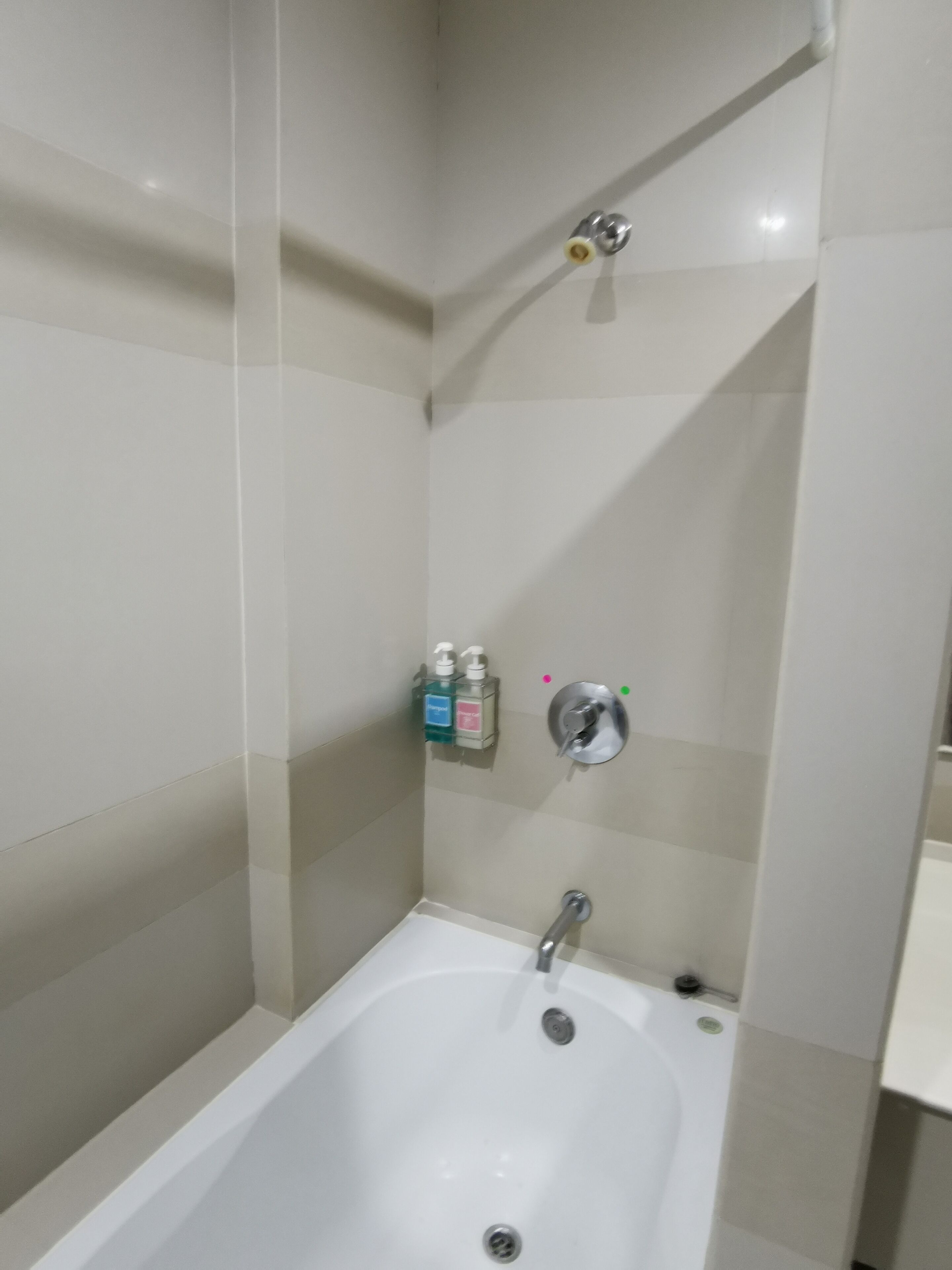 Un baño con bañera, ducha y dispensador de jabón en la pared.