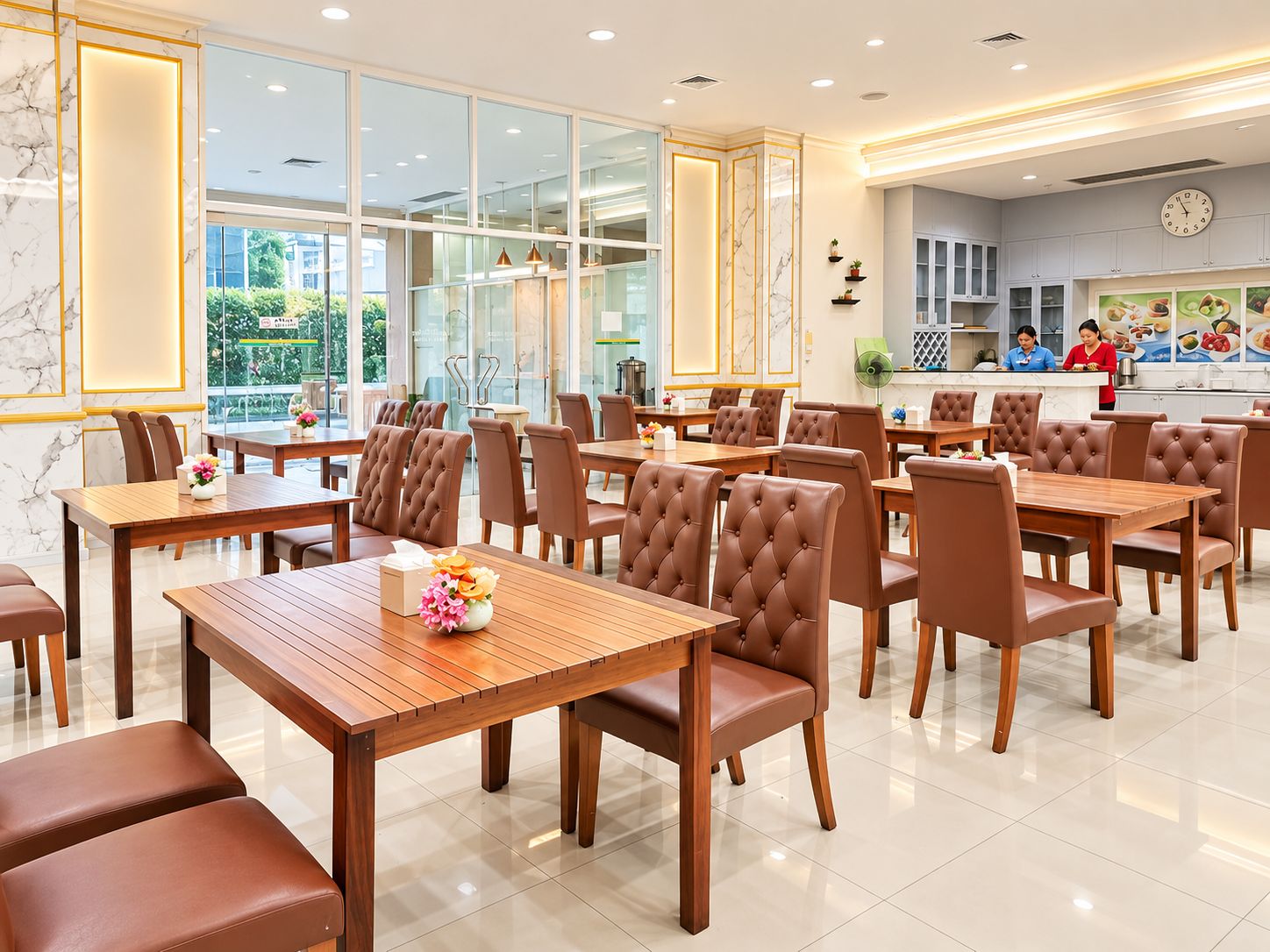 A restaurant with multiple dining tables and chairs, a kitchen area, and a view of the outdoors through large windows.