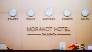 Un comptoir d’accueil d’hôtel avec des horloges indiquant l’heure à Sydney, Tokyo, Bangkok, Londres et Le Caire.