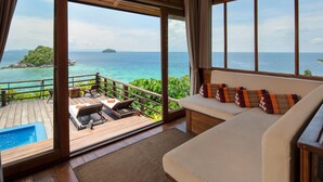 A wooden deck with a pool, a sofa with patterned cushions, and a view of the ocean and a small island. - Serendipity Beach Resort Koh Lipe (Koh Lipe)