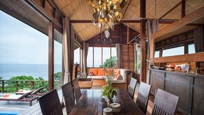A wooden dining area with a view of the ocean, a pool, and a seating area with cushions. - Serendipity Beach Resort Koh Lipe (Koh Lipe)