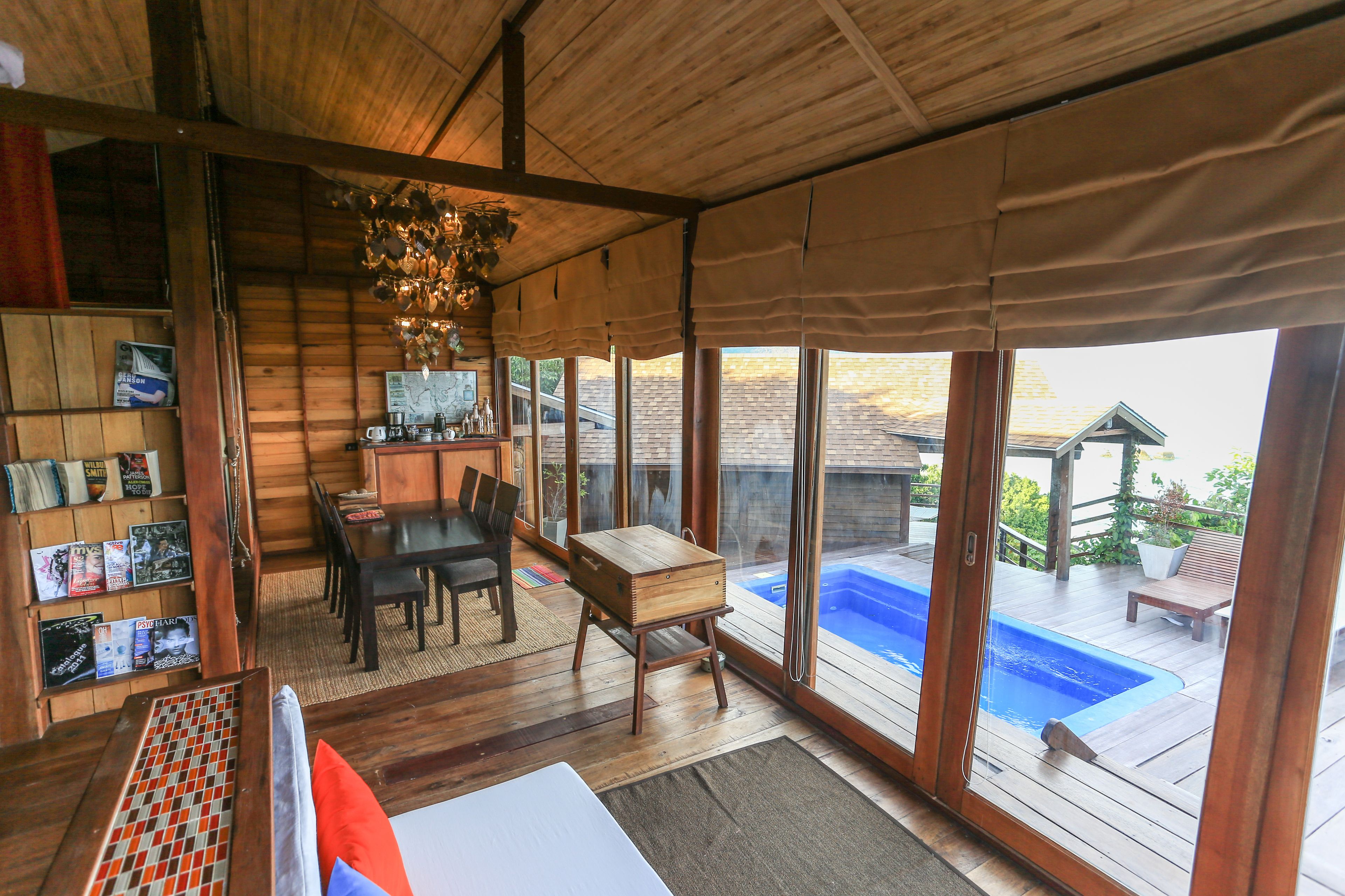 A wooden interior with a dining area, a small table, and a view of an outdoor swimming pool.