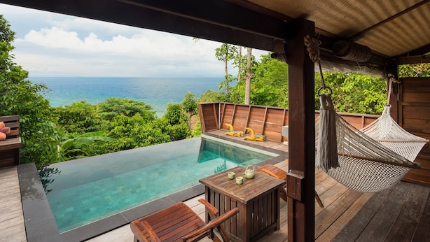 A wooden deck with a glass-bottomed infinity pool, wooden furniture, and a hammock. - Serendipity Beach Resort Koh Lipe (Koh Lipe)