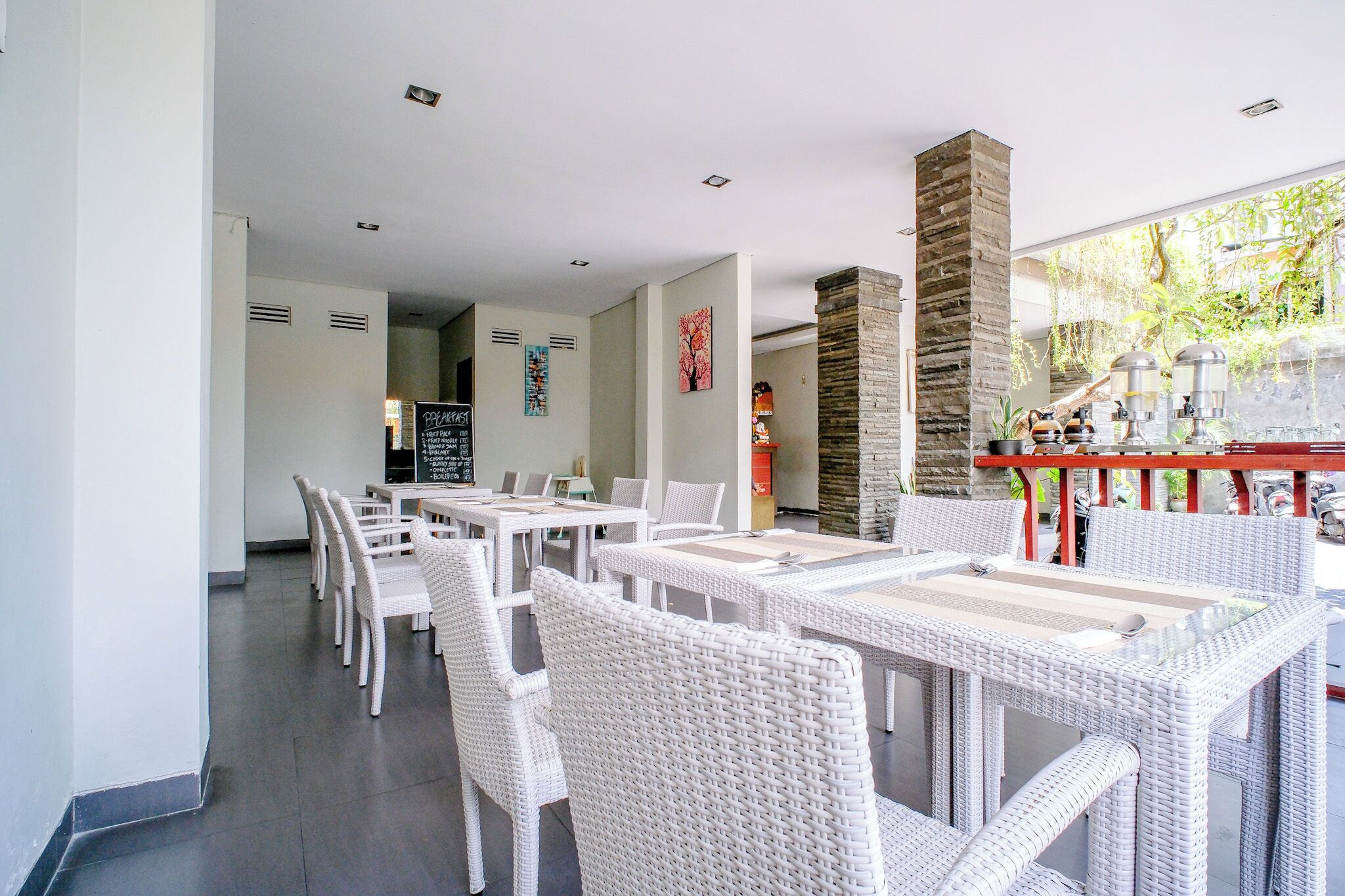 A modern dining area with white wicker furniture and a stone pillar.