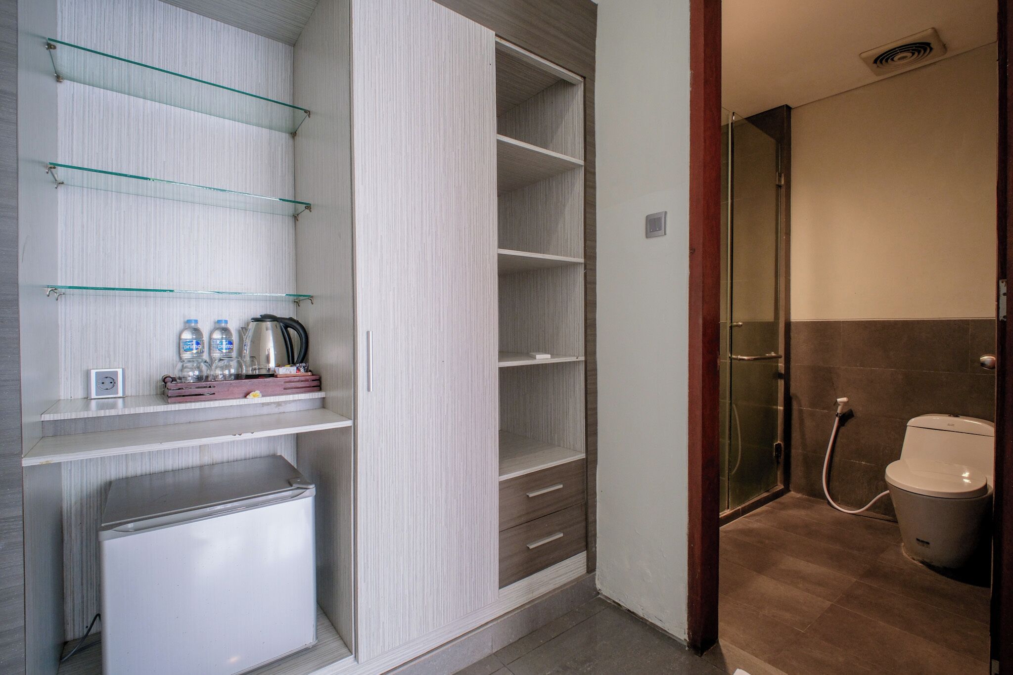 Un baño pequeño con ducha, inodoro y un refrigerador.