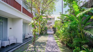 A pathway leading to a building with a balcony and seating area. - Kamini Legian Hotel (Kuta)