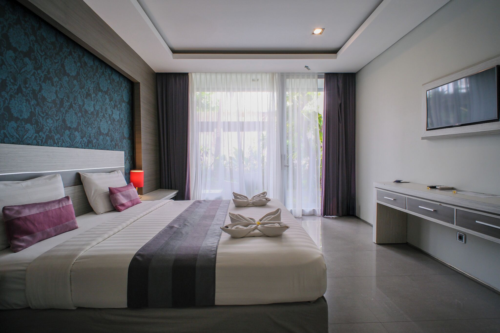Una habitación de hotel moderna con una cama grande, un escritorio y un televisor.