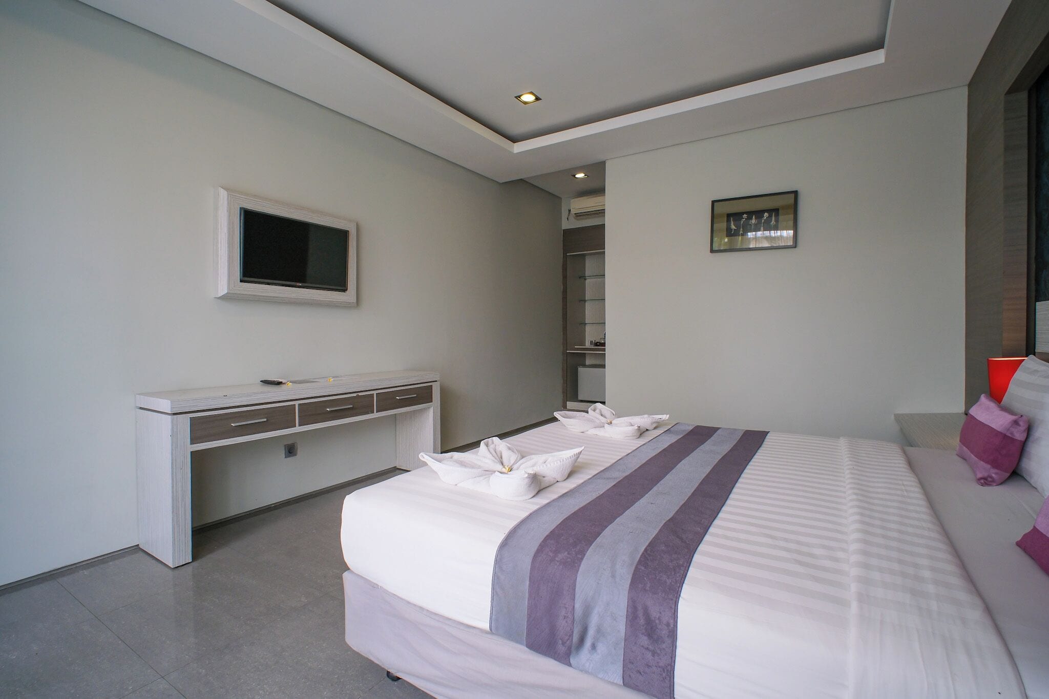 Una habitación de hotel moderna con una cama grande, un escritorio y televisión.