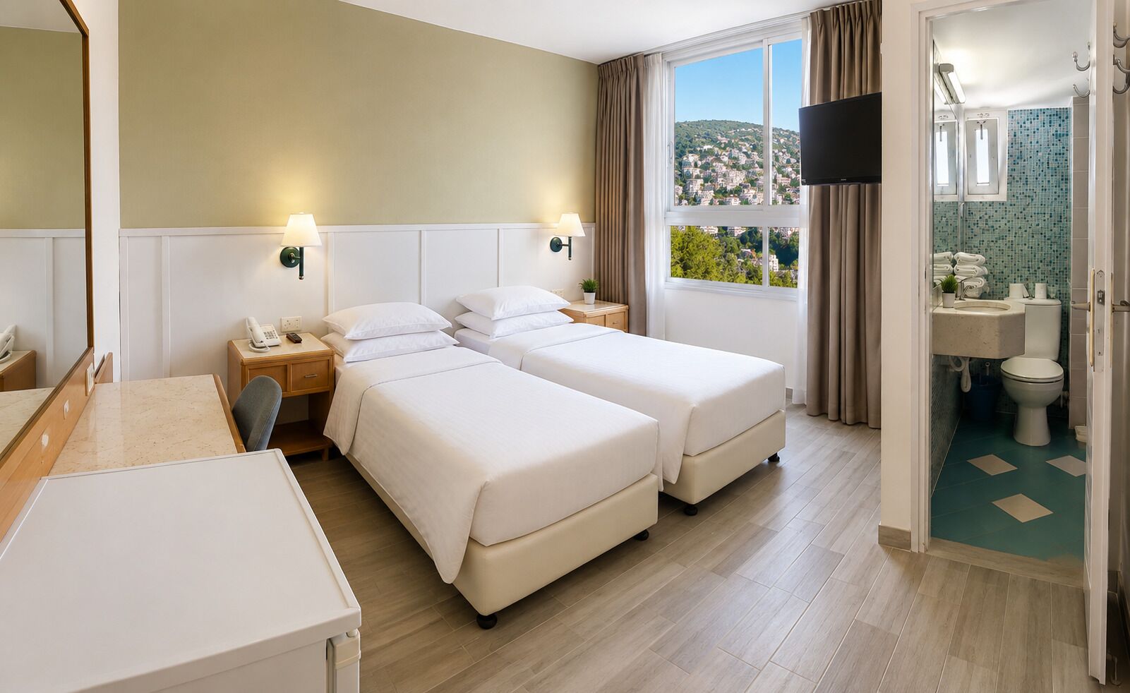 A hotel room with two beds, a desk, a telephone, a TV, and a bathroom with a view.