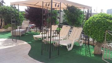 A covered outdoor seating area with lounge chairs and a pergola structure.