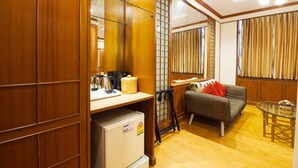 A compact living space with a kitchenette, a sofa, a dining table, and a sliding door leading to a balcony. - Chinatown Hostel (Bangkok)