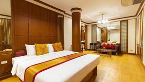 A hotel room with a large bed, wooden paneling, a sitting area with a sofa and table, and a large mirror. - Chinatown Hostel (Bangkok)