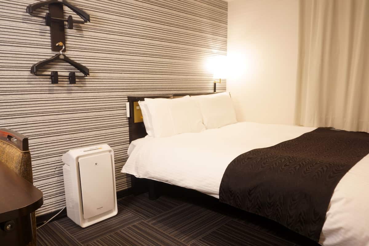 Una habitación de hotel con una cama, un aparador, un radiador y una pared con diseño a rayas.