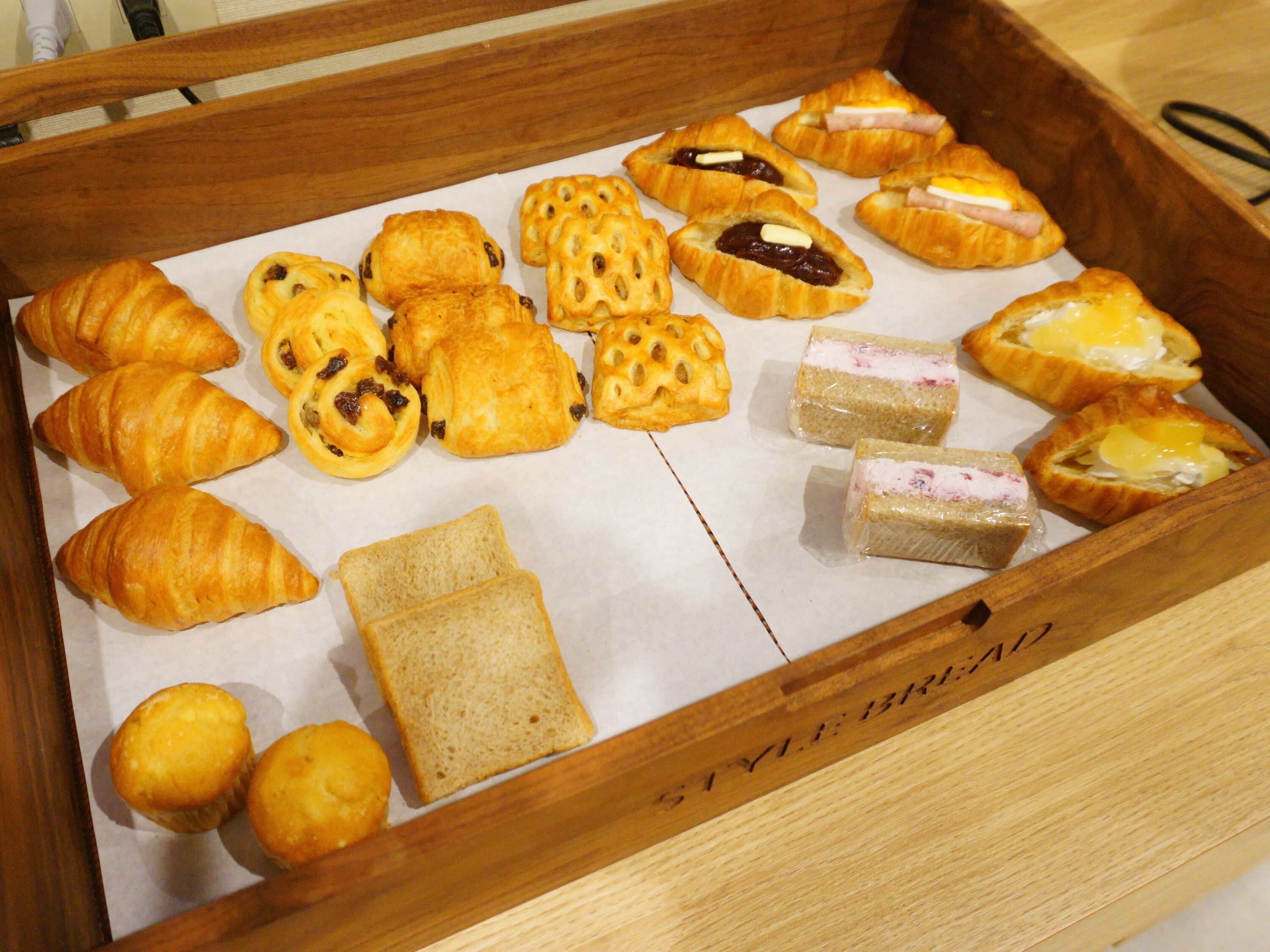Een houten dienblad met diverse gebakjes en brood.