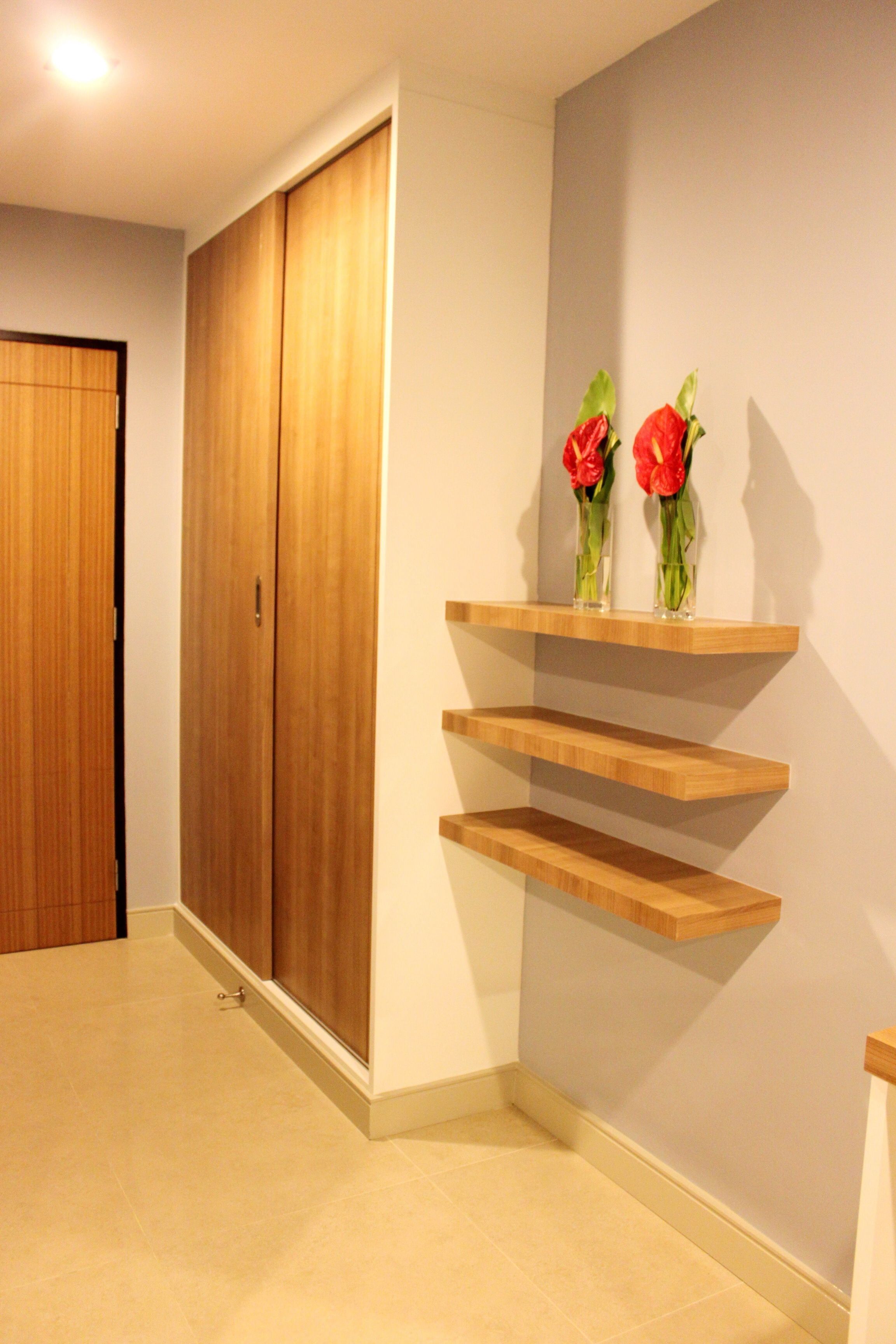 Un couloir doté d’un plancher en bois, d’une porte coulissante et d’étagères en bois sur lesquelles sont posés des vases.