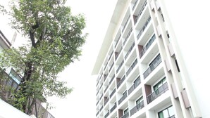 Un immeuble à plusieurs étages doté de balcons, d’une cour pavée et d’un arbre.