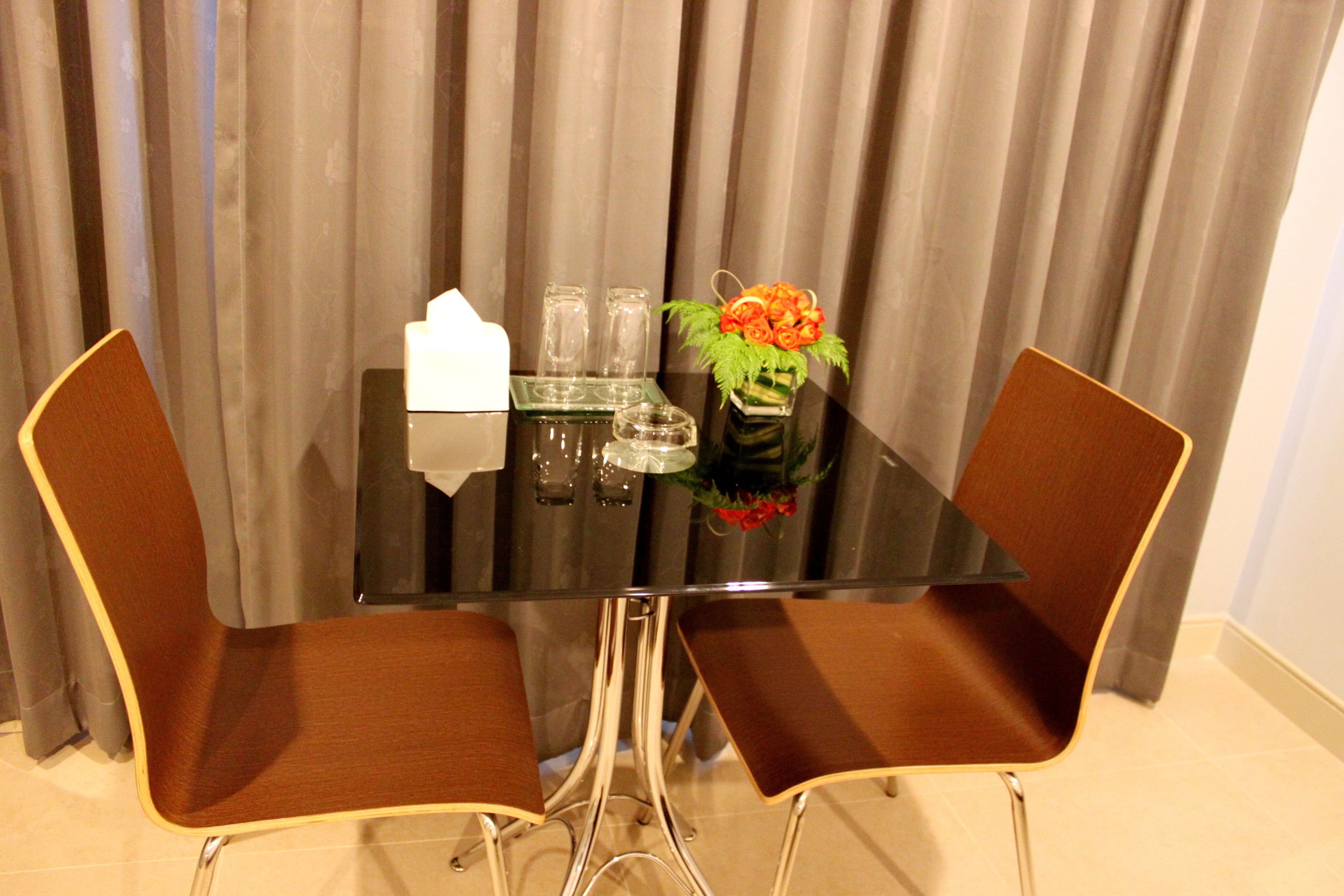 A dining table with two chairs, a vase with flowers, and a tissue box.