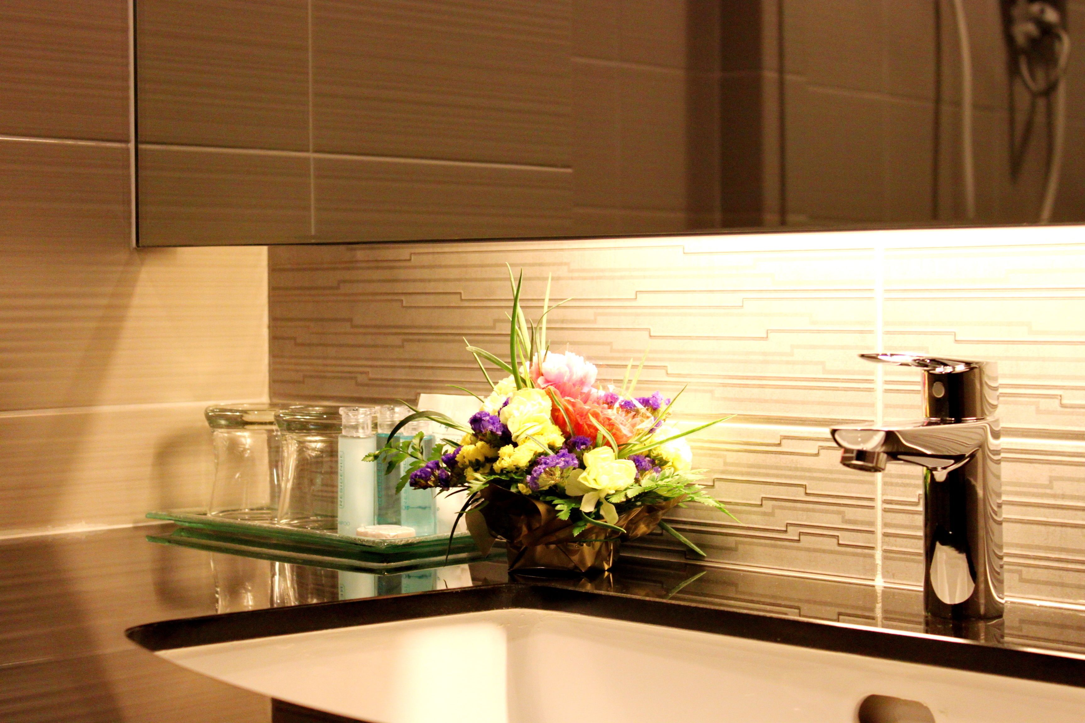 A modern kitchen with a stainless steel sink, a glass dish rack, and a decorative flower arrangement on the counter.