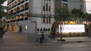 Un hôtel à plusieurs étages, reconnaissable à son grand panneau indiquant « RÉSIDENCE », à ses nombreux balcons et à son entrée bien éclairée.