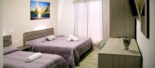 Une chambre d’hôtel avec deux lits, un bureau, une télévision et un tableau au mur.