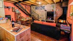 A cozy interior with a stone fireplace, wooden beams, a dining area, and a staircase. - Entre Valles (Carrocera)