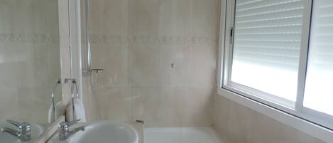 A bathroom with a sink, mirror, shower, and bathtub.