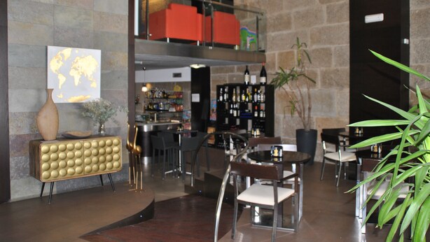 A modern lobby with a bar area, seating, and a world map artwork on the wall. - Hotel Junquera (Vigo)