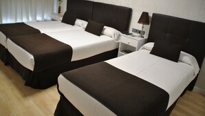 A hotel room with two beds, a nightstand, a lamp, and a wall with city names. - Hotel Junquera (Vigo)