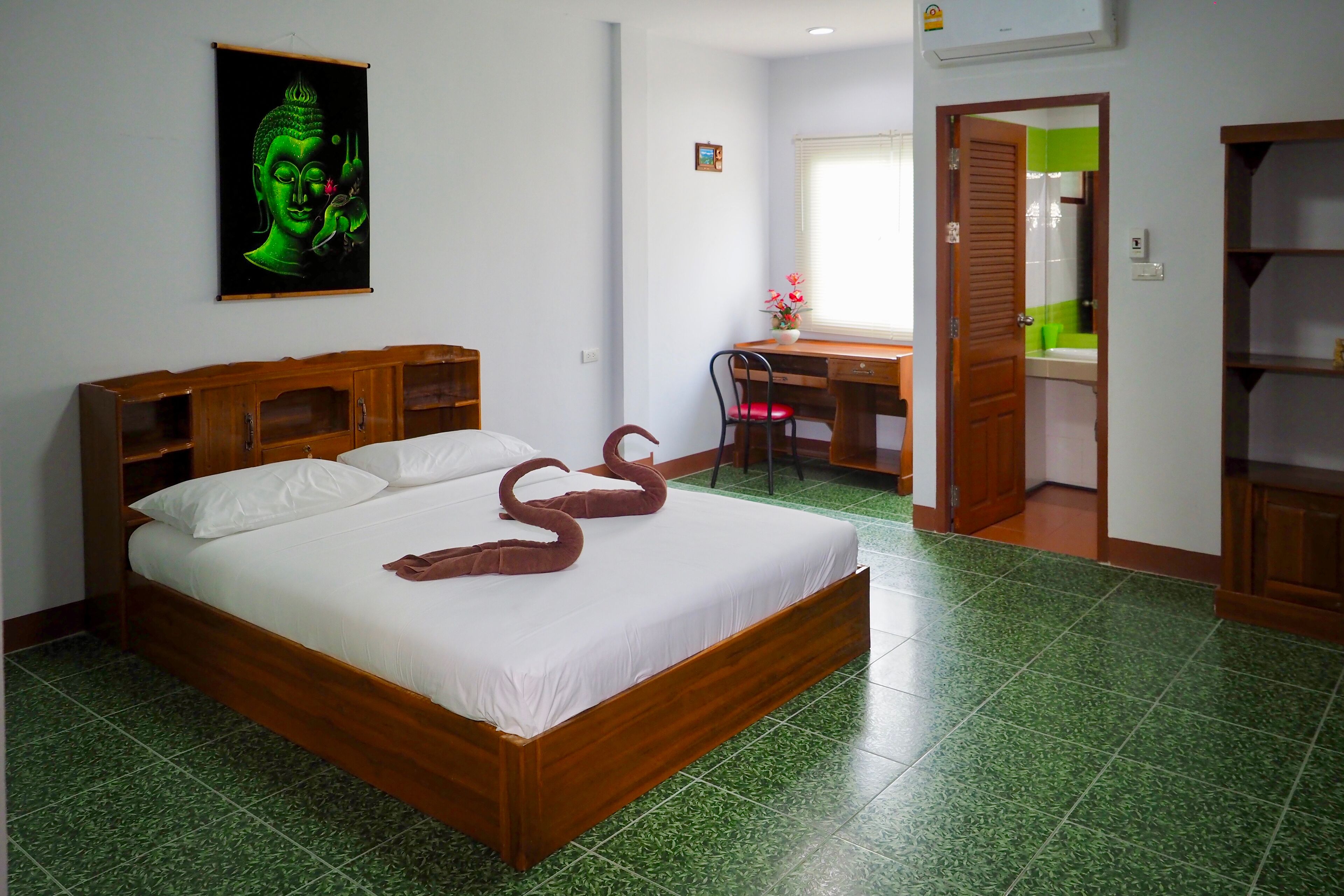 A hotel room with a bed, a desk, and a bathroom visible through an open door.