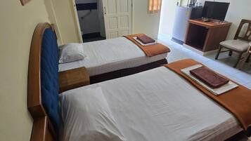 Ein Hotelzimmer mit zwei Betten, einem Schreibtisch, einem Fernseher und einem Kleiderschrank.