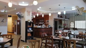 Restaurante com mobiliário de madeira, área de bar e iluminação pendente.