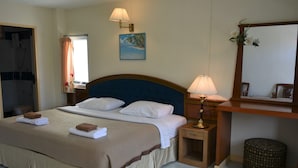 Quarto de hotel com cama, abajures, um quadro, um espelho e um banquinho.