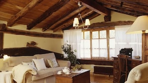 Una sala de estar acogedora con techo de madera, un sofá, una mesa de centro y un sillón.
