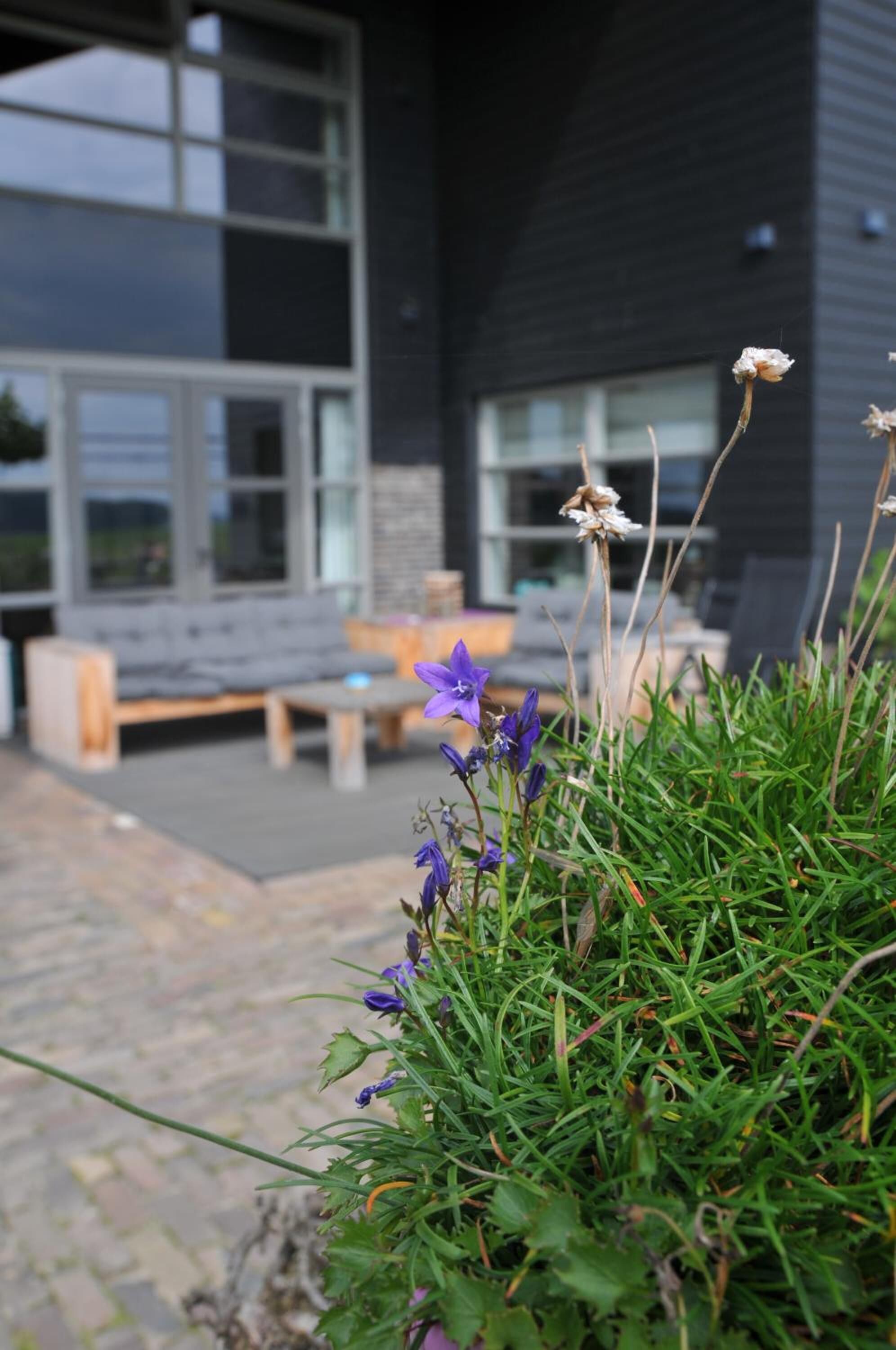 Een modern gebouw met grote ramen en een patio met een bankje en een tafel.