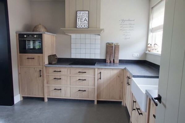 A kitchen with wooden cabinets, a built-in oven, and a sign on the wall.