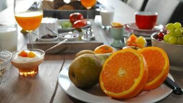 A breakfast table with fruits, a glass of orange juice, and a bowl of grapes.