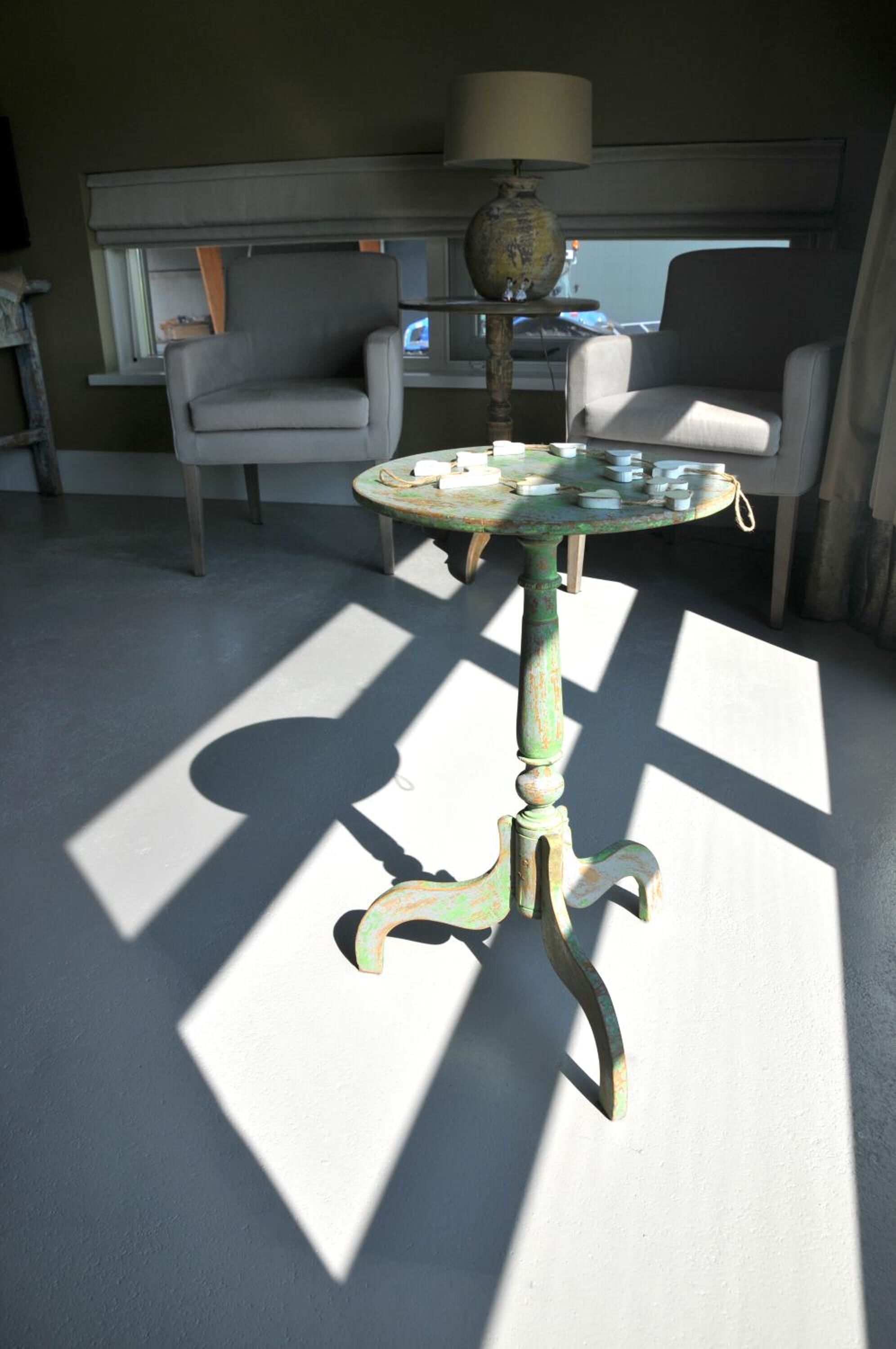 Una mesa antigua con una lámpara, dos sillas y una ventana en una habitación.