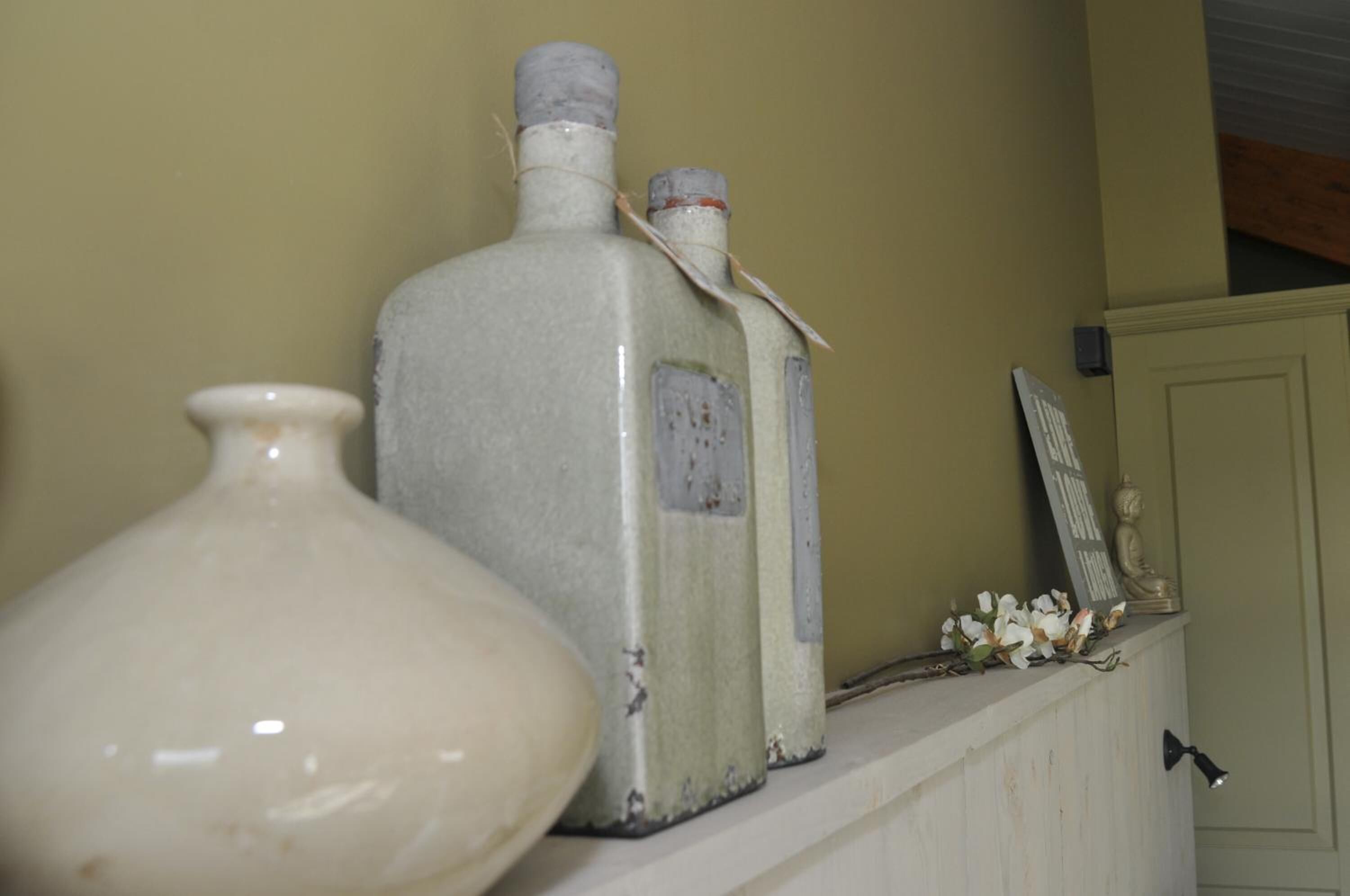 Una estantería con dos botellas y un florero.