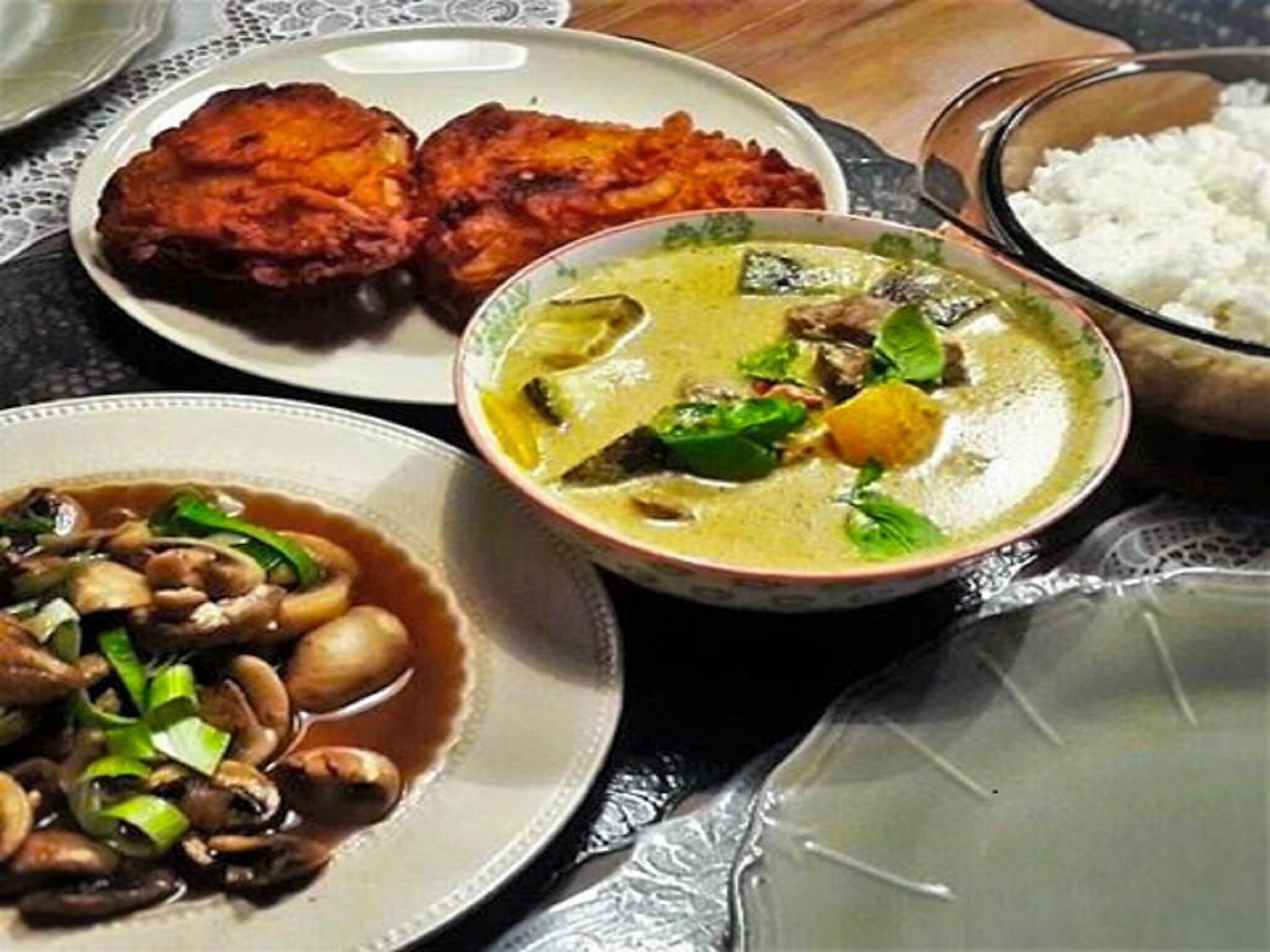Una mesa con diversos platos, incluyendo un tazón de sopa, una bandeja de alimentos fritos y un plato de champiñones.
