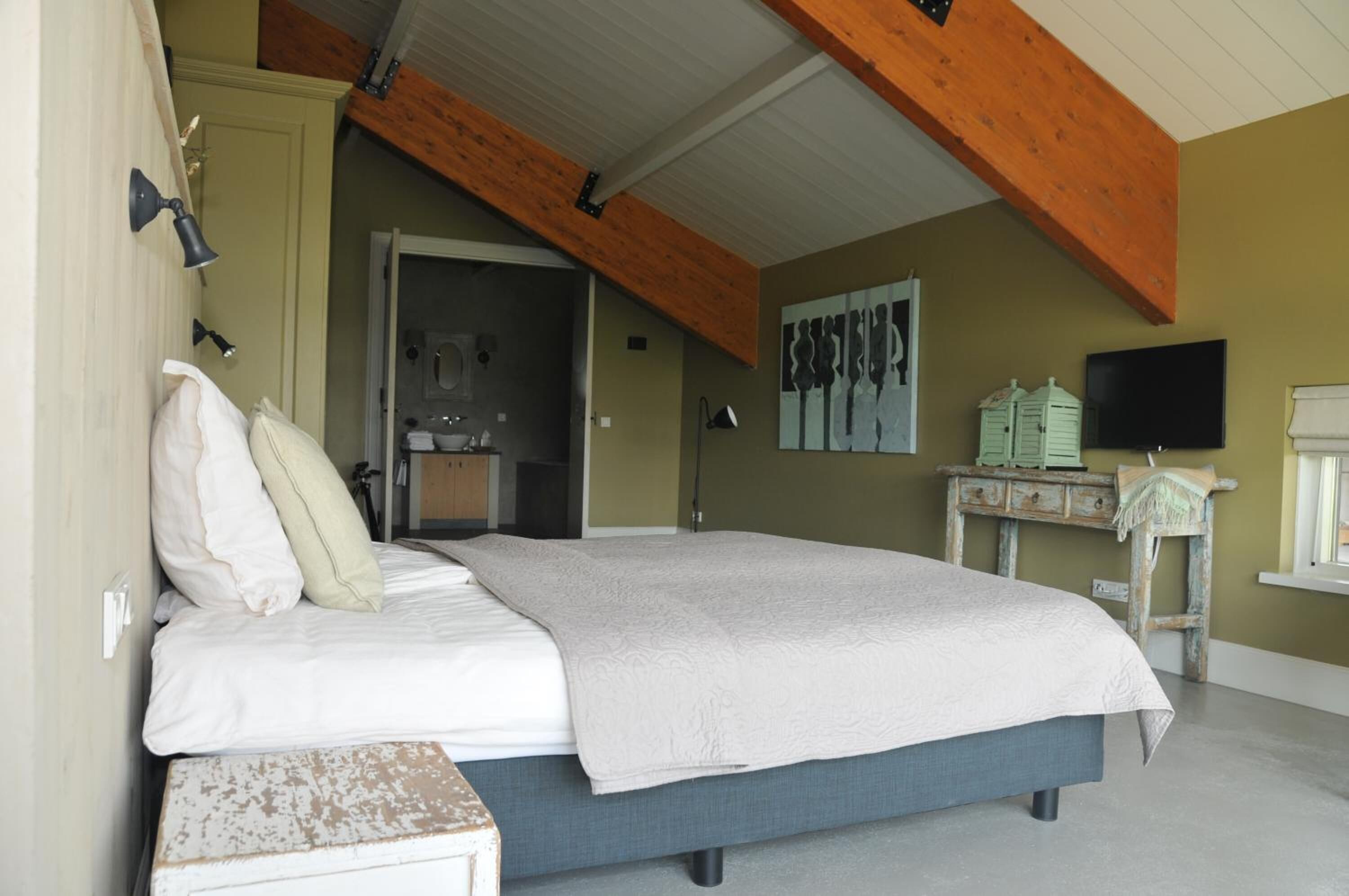 Un dormitorio con cama, techo de madera, televisor y ventana.