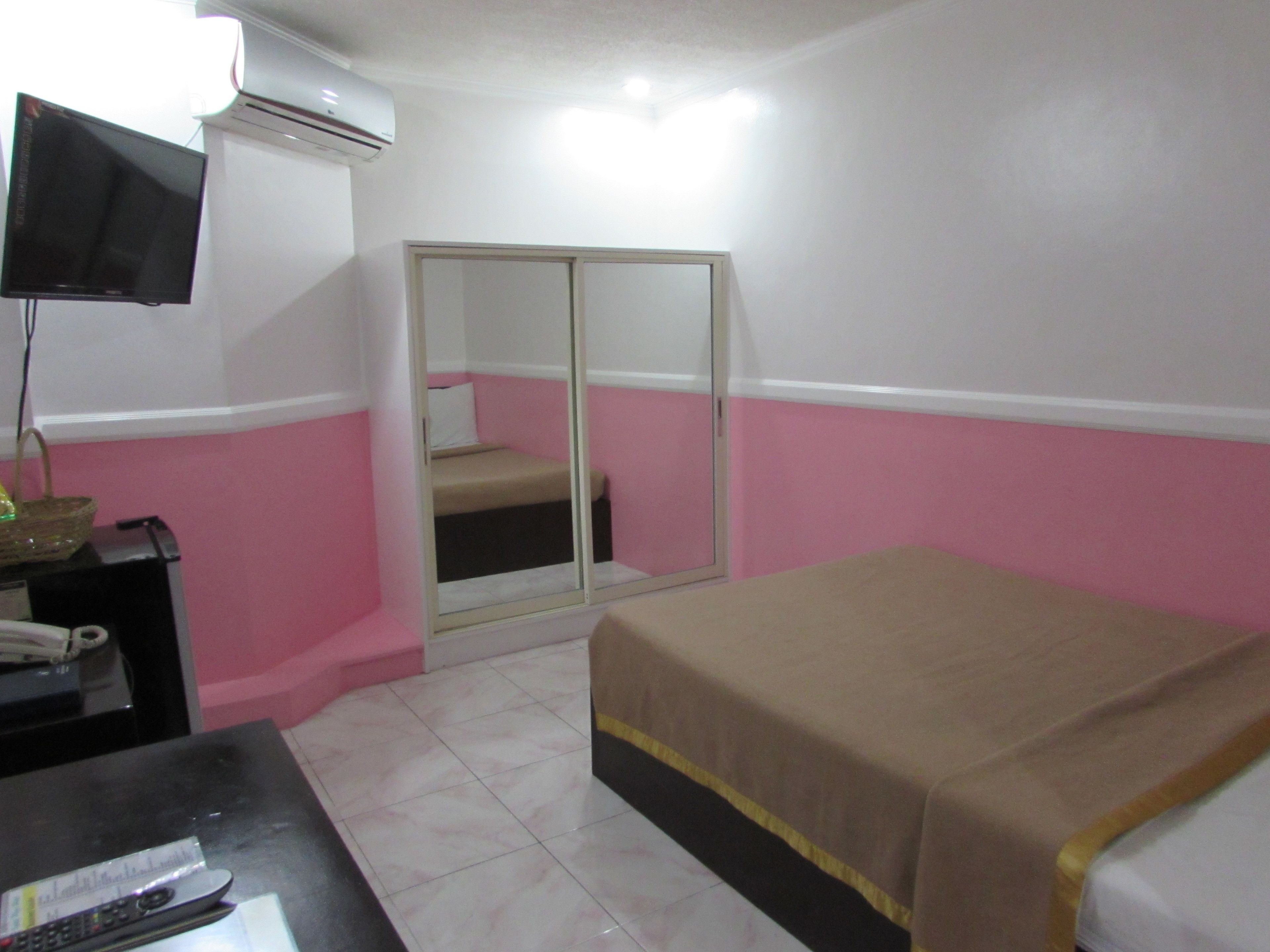 Una habitación de hotel con cama, escritorio con computadora, televisor y armario.