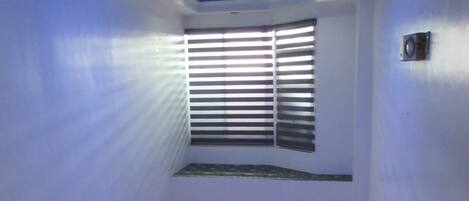 A staircase with a metal railing, a chandelier, and a window with blinds.
