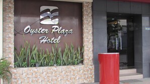 Das Oyster Plaza Hotel mit einer Stein-Fassade und einer großen roten Säule im Vordergrund.