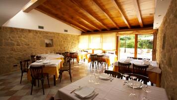 Un restaurante con paredes de piedra, vigas de madera y mesas dispuestas para comer.