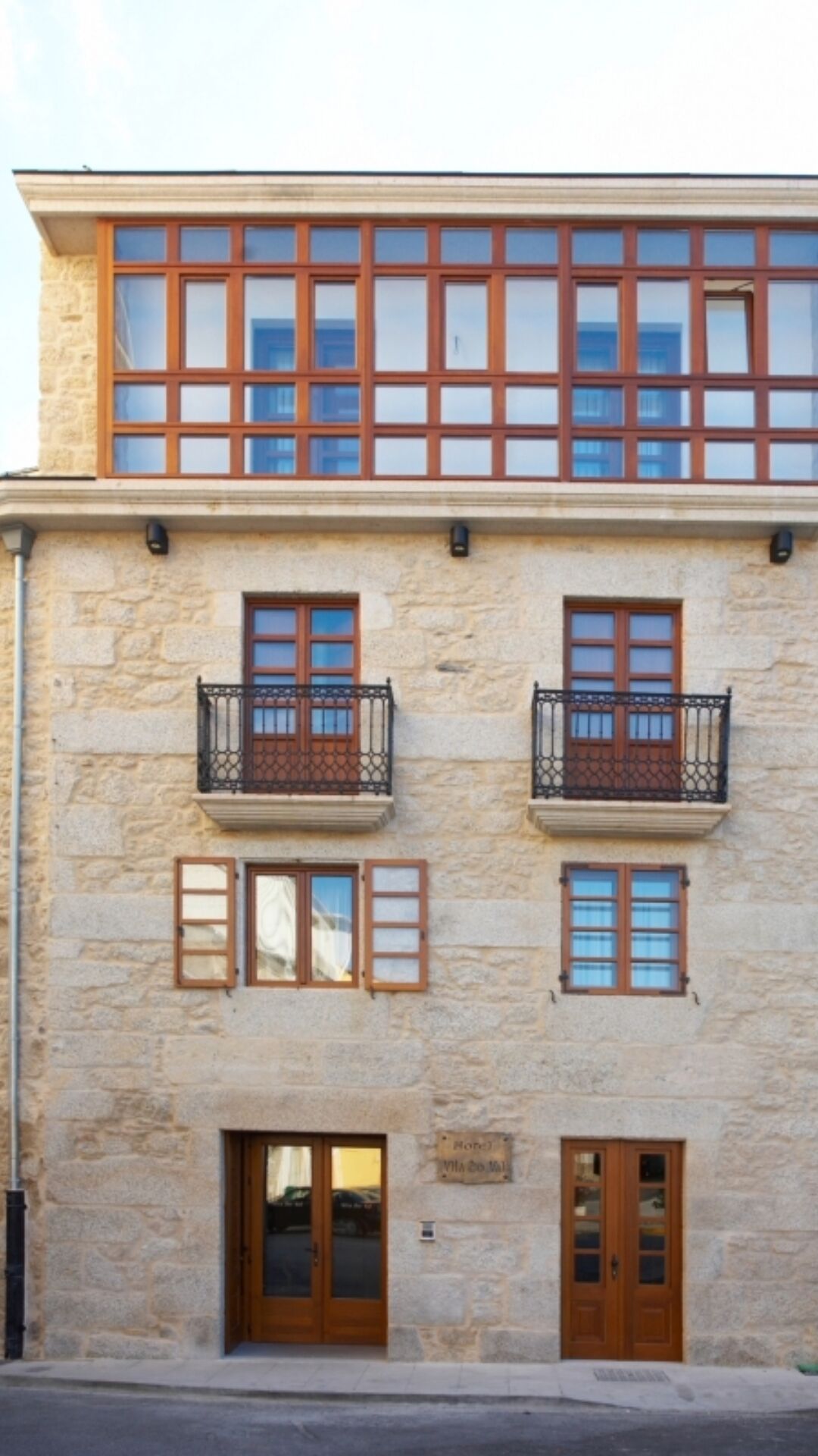 Un immeuble à deux étages, doté d’une façade en pierre, de nombreuses fenêtres et de balcons.
